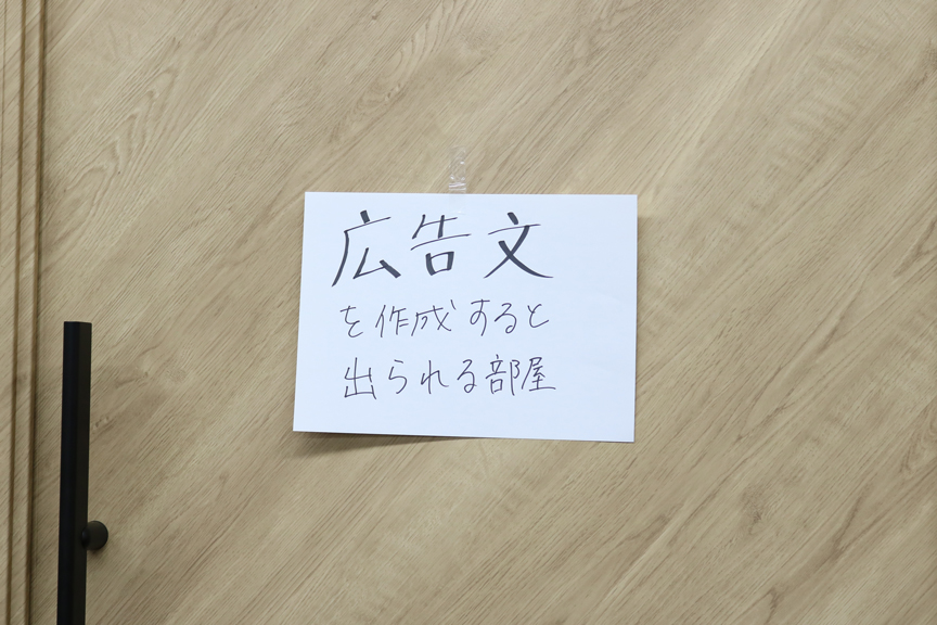 ドアの真ん中に白い紙が貼られている。紙には「広告文を作成すると出られる部屋」の手書き文字。